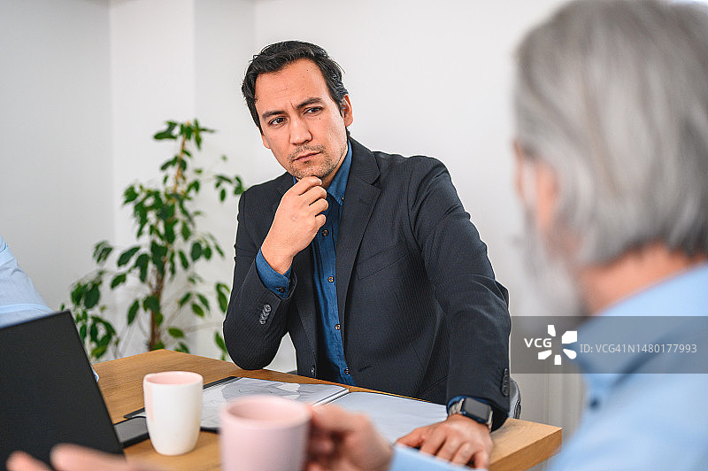 倾听经理讲话且手托下巴的沉思日本商人图片素材