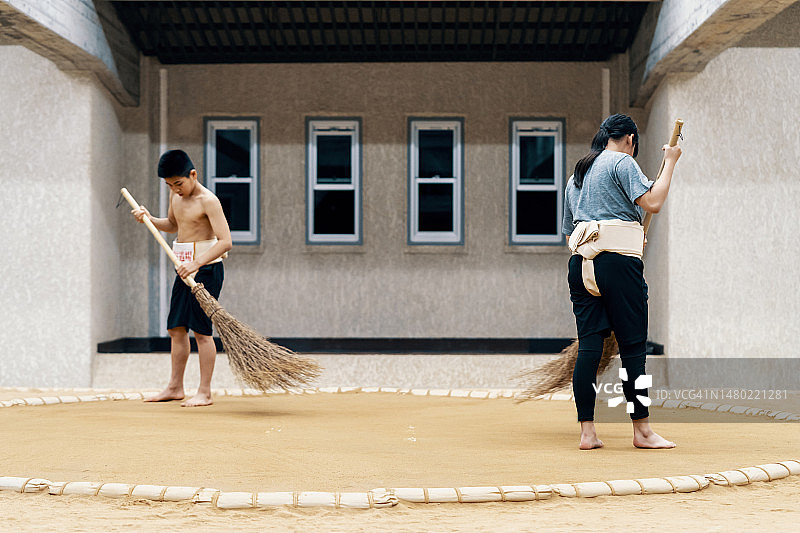 年轻学生在相扑练习前清扫和准备土俵图片素材