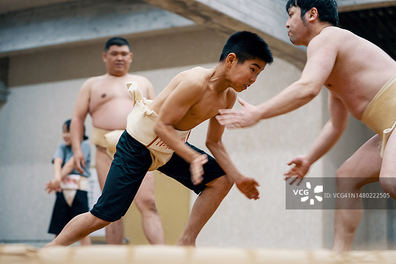 相扑练习中与教练摔跤的年轻男孩图片素材