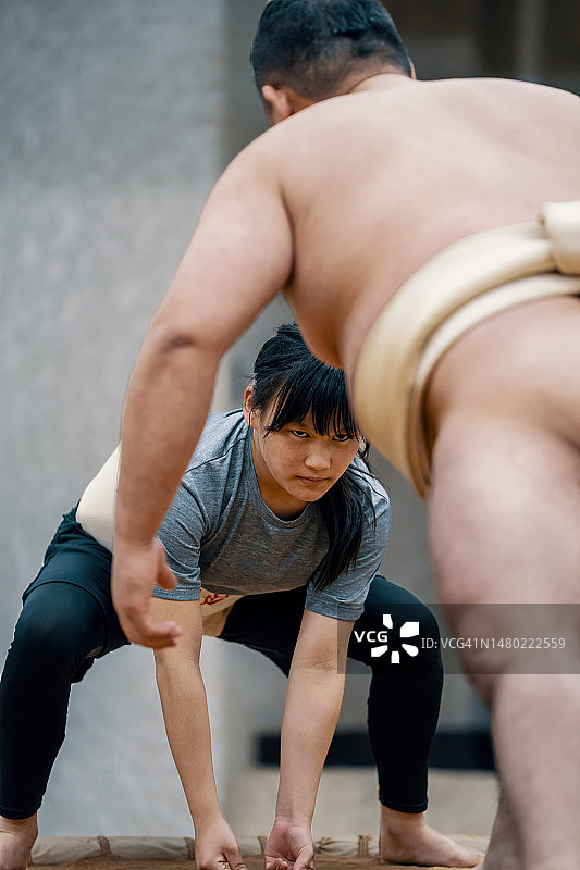 小学年龄的女孩在相扑练习中与教练摔跤图片素材