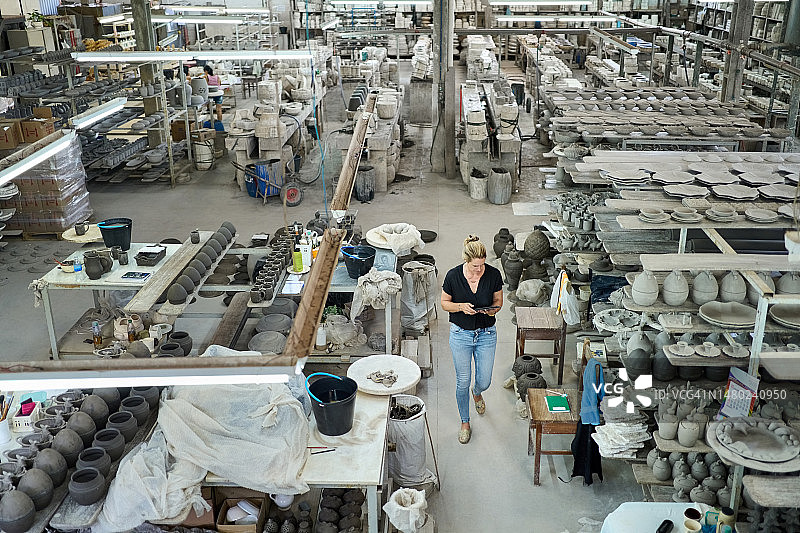 女人在陶瓷厂生产线上使用平板电脑图片素材