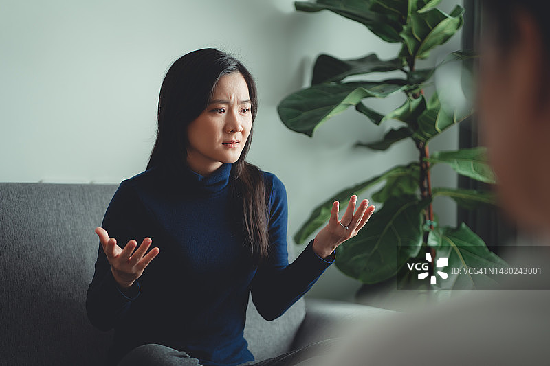亚洲女性在咨询办公室的沙发上与心理医生讨论婚后问题图片素材