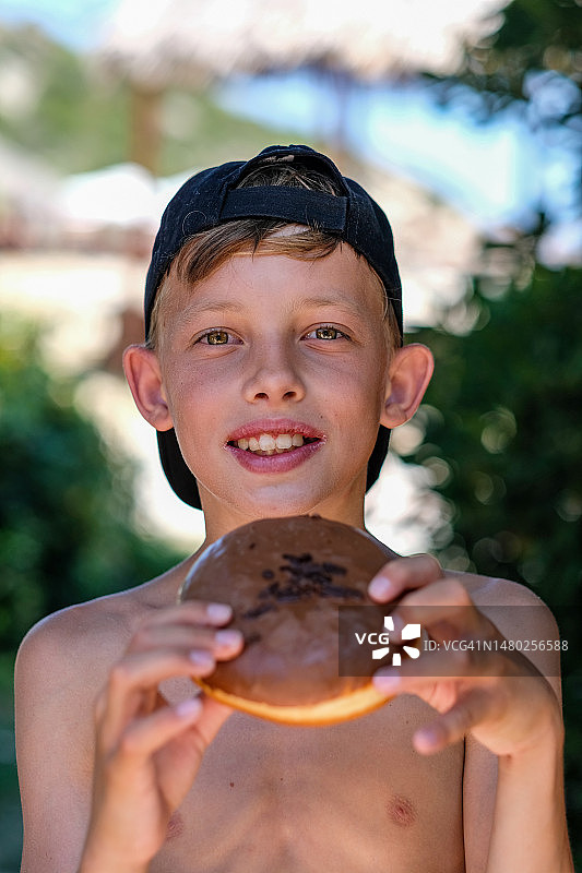 男孩在沙滩上吃甜甜圈图片素材