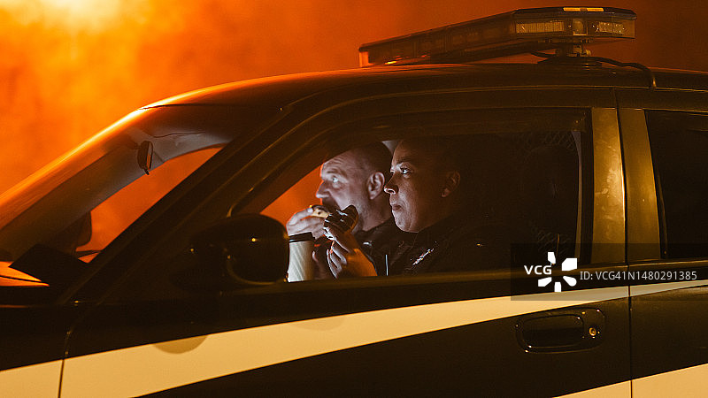 两名警官在雾夜坐在车里吃甜甜圈，在街上巡逻图片素材