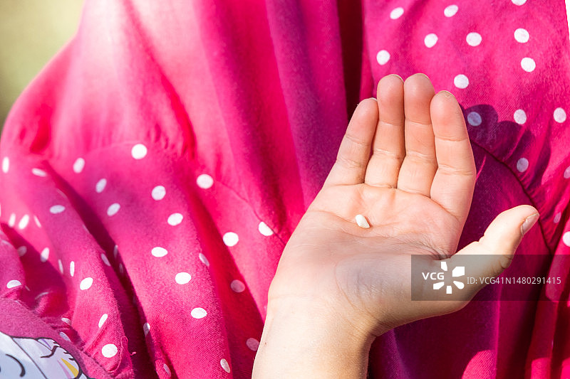 女孩手心拿着掉落的乳牙，换牙期图片素材