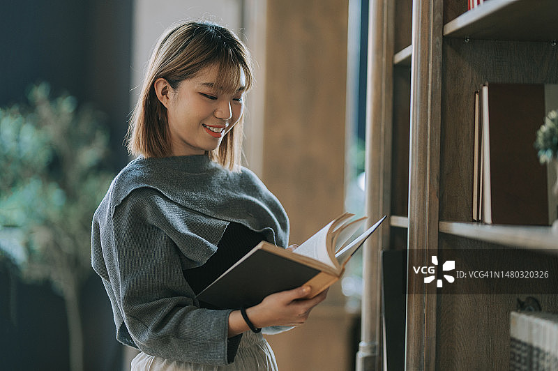 在图书馆看书的亚洲年轻女子图片素材