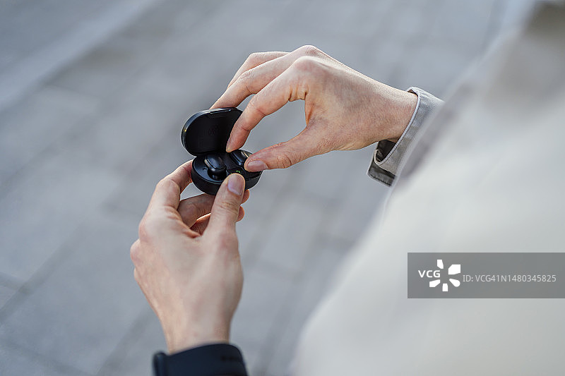 男子从充电盒中取出无线耳机图片素材