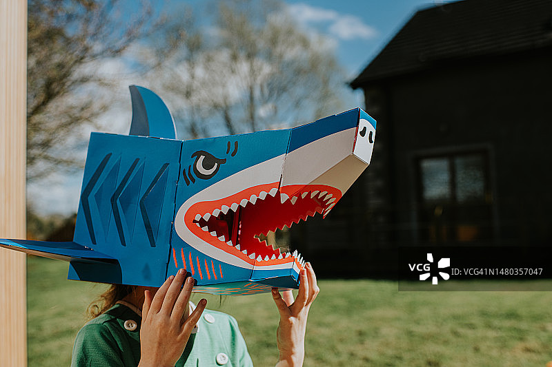 戴彩色纸板鲨鱼面具的儿童侧面图片素材