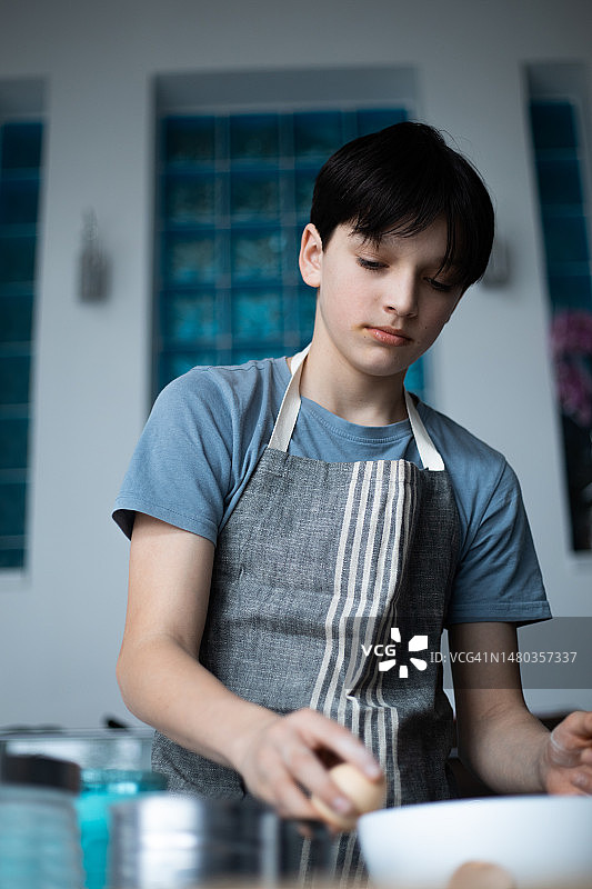 可爱的青少年在碗边打鸡蛋的肖像图片素材