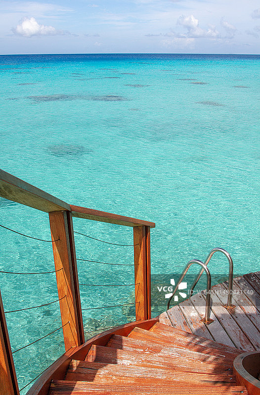 通往清澈碧绿泻湖水面的木制楼梯图片素材