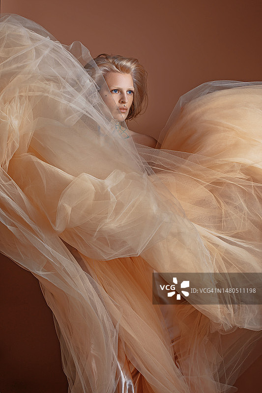 一位穿着奶油色连衣裙的漂亮金发女人图片素材