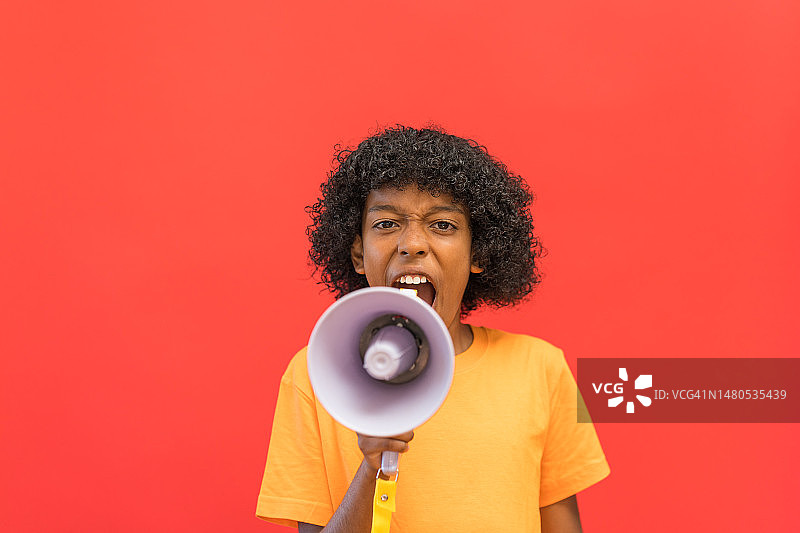 一个11岁男孩充满活力地对着扩音器喊叫图片素材