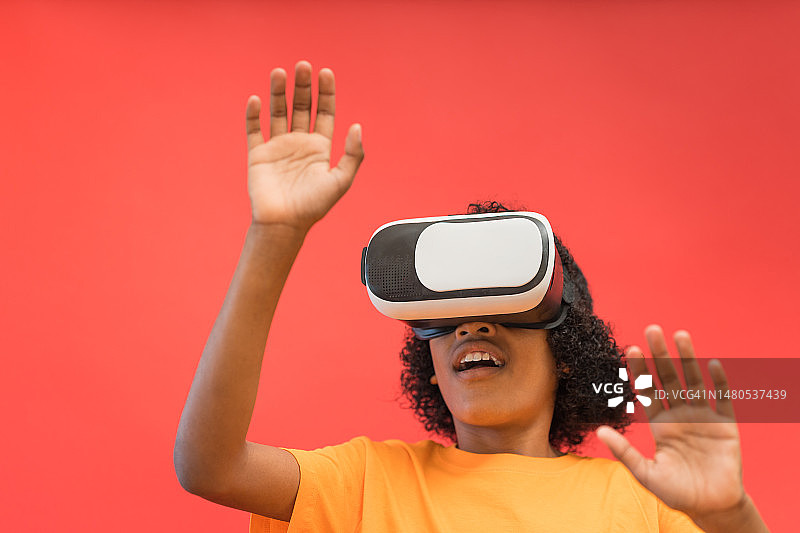 红色背景下戴VR头显的男孩图片素材