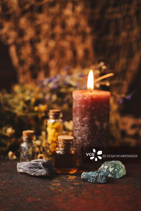 石头、装有油和草药的罐子、燃烧的蜡烛、干燥的植物图片素材