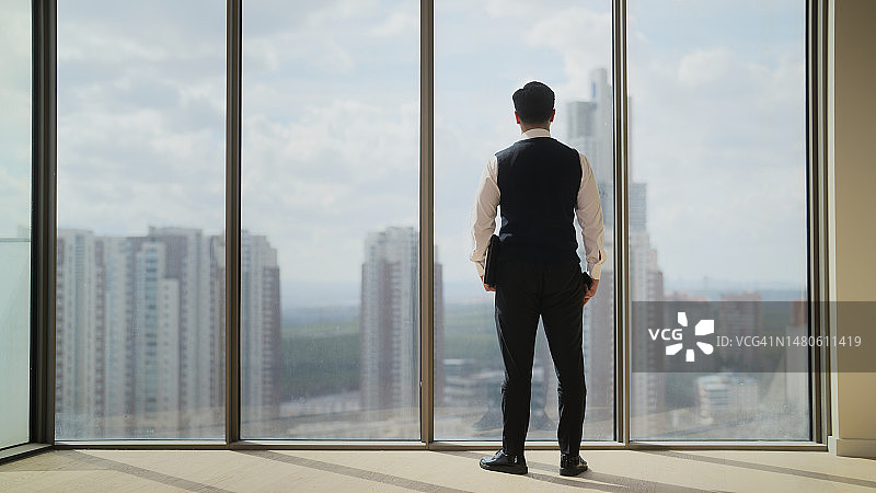站在窗边向外看的商务男士全身像图片素材