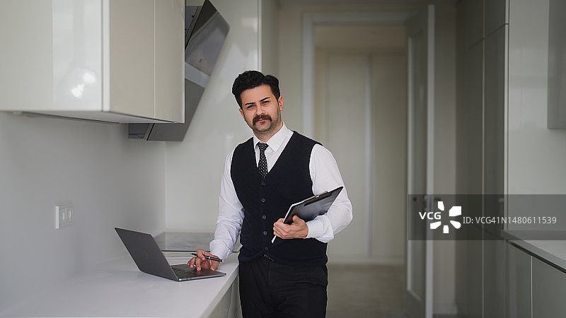 在厨房手拿文件的男性房地产经纪人肖像图片素材