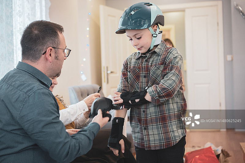 父亲帮助儿子穿戴新的护膝和护臂图片素材