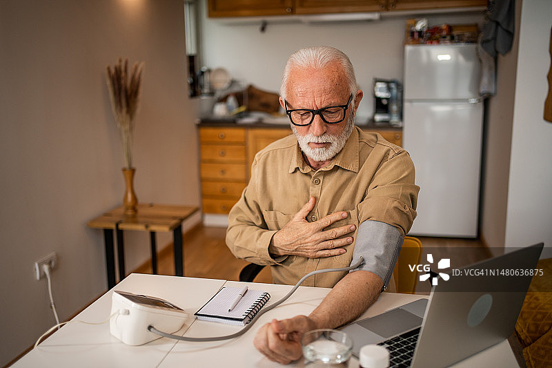年长的男人用电子血压计测量血压图片素材