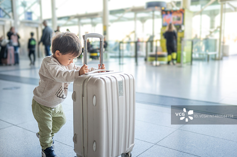 可爱的男婴在机场推着小型行李箱图片素材