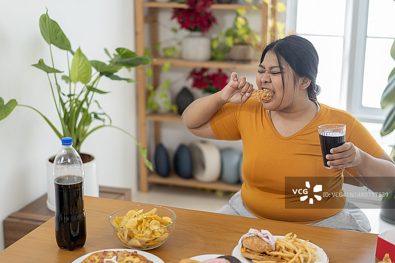 饥饿的超重女人拿着炸鸡图片素材