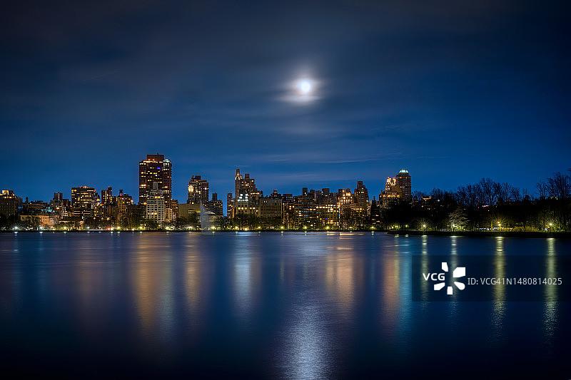 在纽约市曼哈顿东区和中央公园杰奎琳·肯尼迪·奥纳西斯水库上空的渐亏凸月图片素材