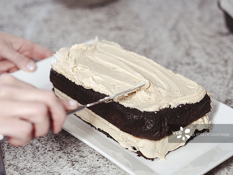 用手给纯素巧克力蛋糕涂上糖霜图片素材