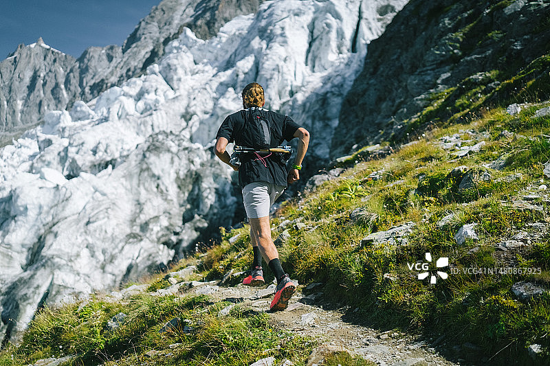 越野跑者在冰川下的小路上飞奔图片素材