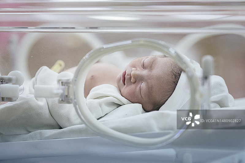 亚洲新生儿在保温箱中熟睡的面部表情和留白图片素材