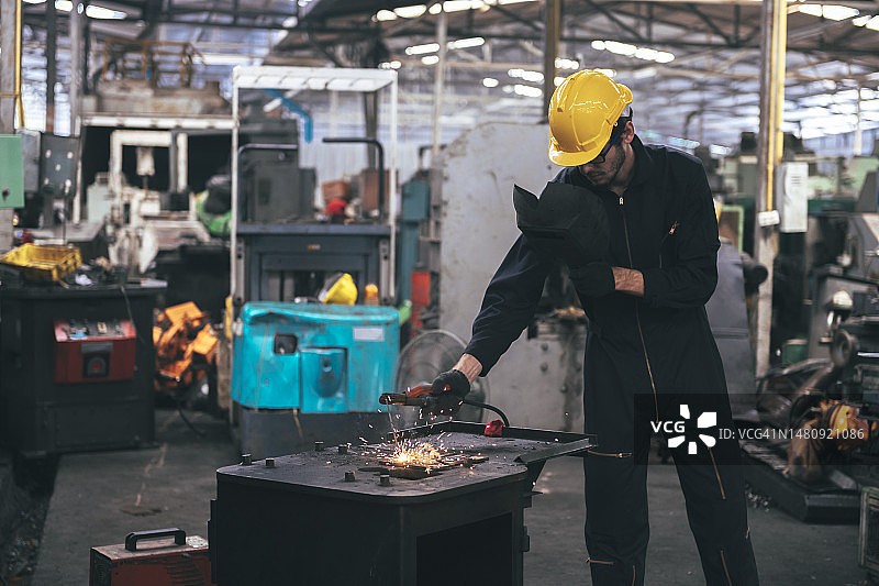 穿防护服、戴防护面罩的白人在工厂焊接钢铁图片素材