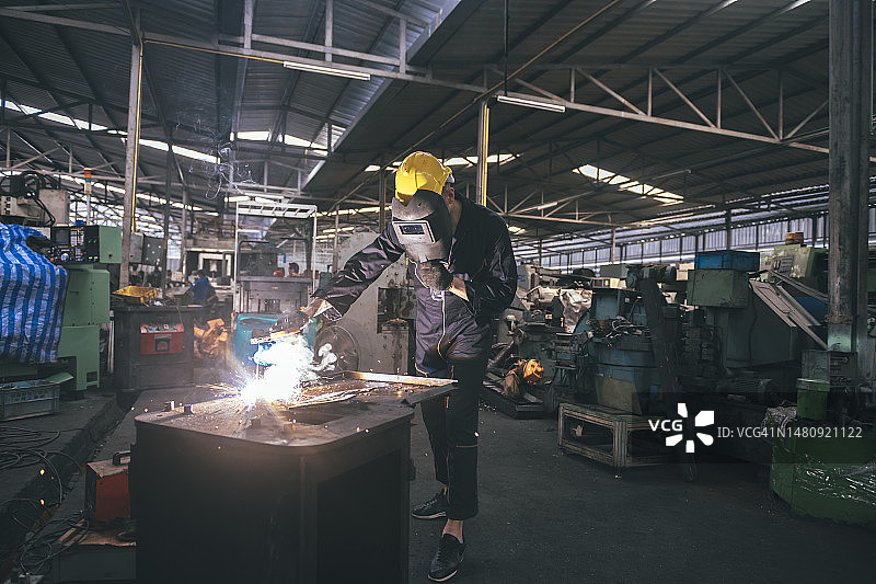 穿防护服、戴防护面罩的白人在工厂焊接钢铁图片素材