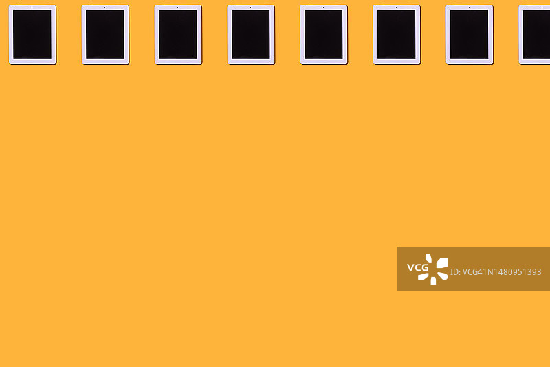 黄色背景上的白色平板电脑图案：智能设备概念图片素材