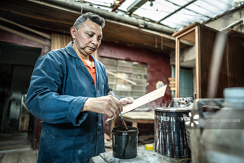 在木工车间涂抹木材的中年男人图片素材