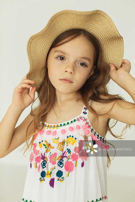 白色背景中戴帽子、穿白色连衣裙的金发女孩图片素材