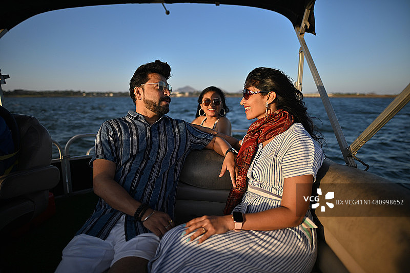 中年夫妇和他们的女儿在湖上享受乘船之旅图片素材