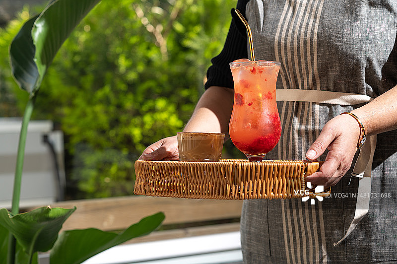 一位女服务员端着一个托盘，里面有一杯鸡尾酒和一杯冰咖啡，café图片素材