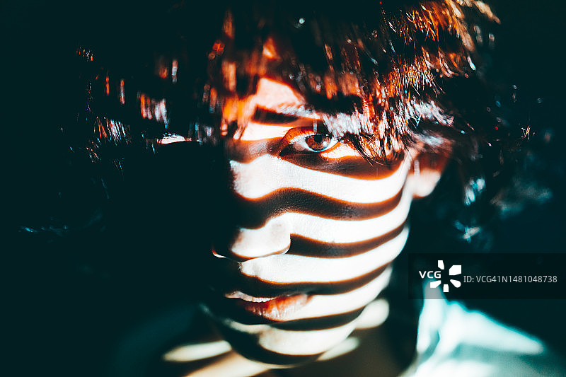 一人在夜晚透过百叶窗盯着相机，电影色调图片素材