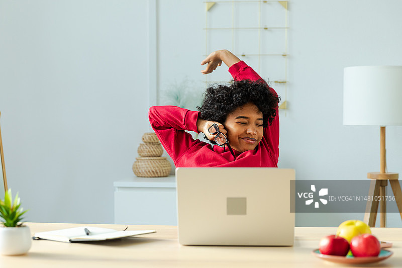 非裔美国女孩在家办公，放松身心，伸展手和身体，从笔记本电脑工作中休息。快乐的年轻自由职业者女商人对工作完成后的良好结果感到满意。图片素材
