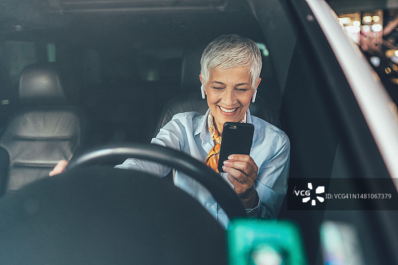 年长的女人在车里使用智能手机图片素材