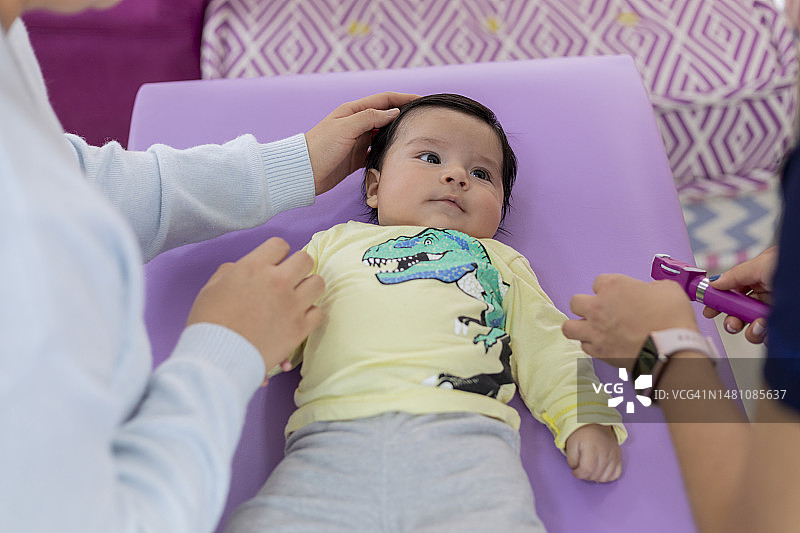 母亲在儿科诊室检查时爱抚她的宝宝图片素材