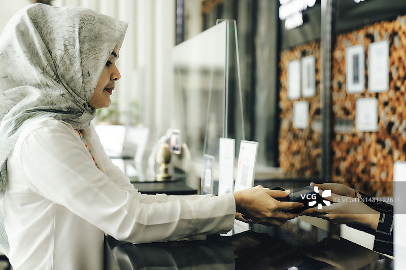 在酒店前台使用非接触式支付的女商人图片素材