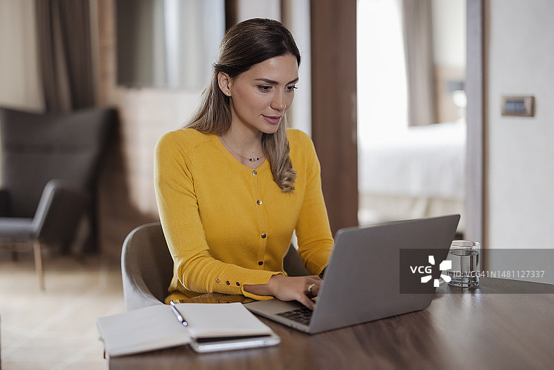 在酒店房间使用笔记本电脑的女商人图片素材
