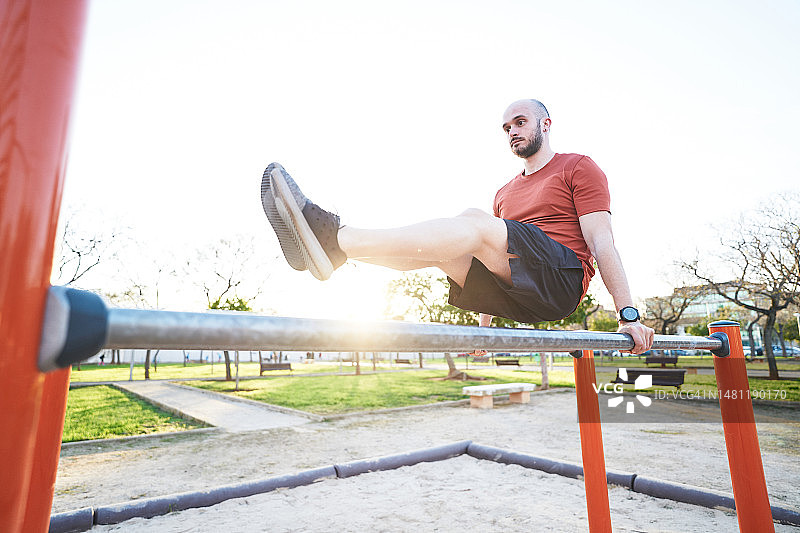 男人在户外健身房使用双杠锻炼图片素材