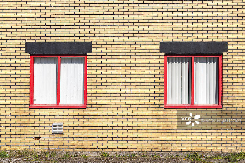 黄色石墙上的四个红色窗户图片素材