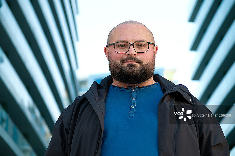戴眼镜的光头年轻男子在街上微笑图片素材