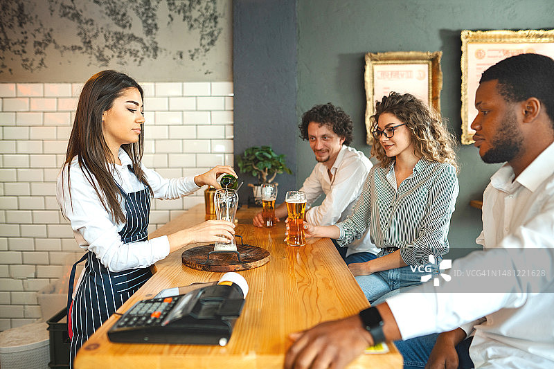 年轻女服务员在酒吧为顾客倒啤酒图片素材