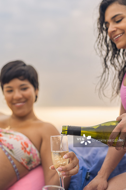 女性在海滩上为朋友们倒香槟图片素材