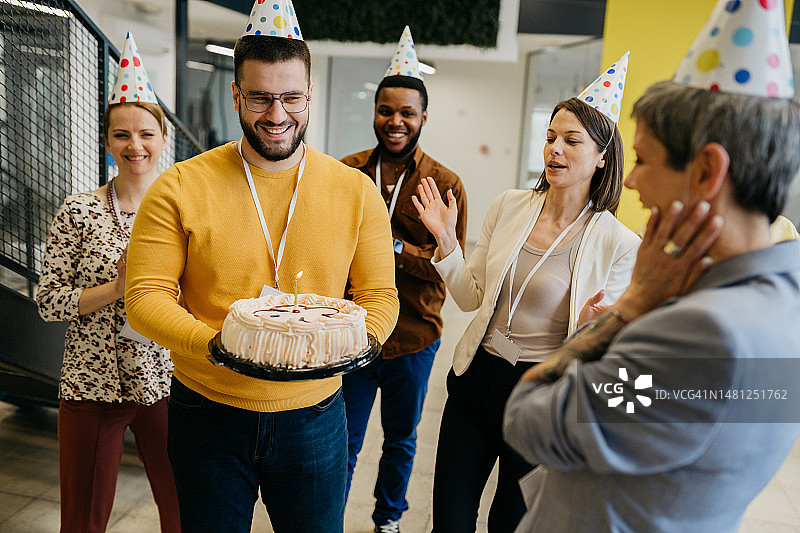 同事们用蛋糕和帽子祝贺同事生日图片素材