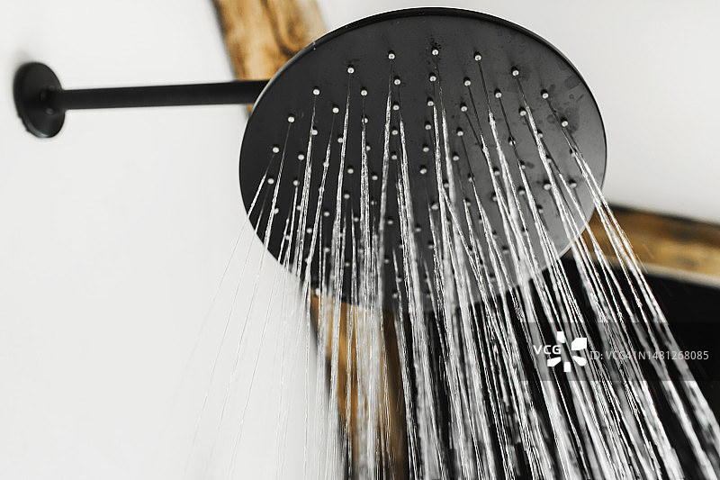 淋浴喷头水滴特写：时尚黑色金属喷头与流动水纹理图片素材