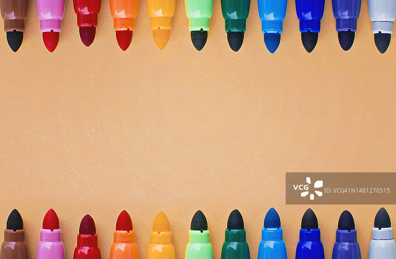 橙色背景上的彩色毡尖笔图片素材