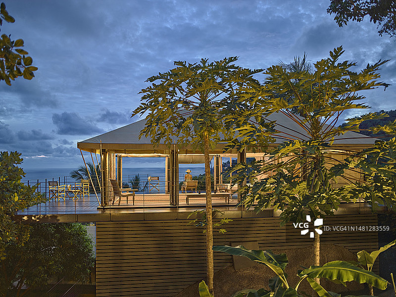 坐在豪华生态露营度假村的帐篷别墅甲板上欣赏海景的女游客图片素材